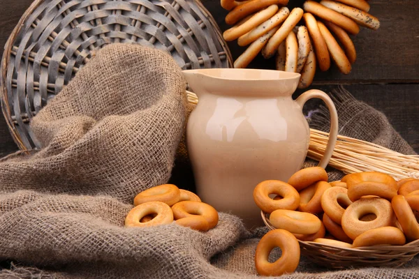 Jar of milk, tasty bagels and spikelets on wooden background — Stock Photo, Image