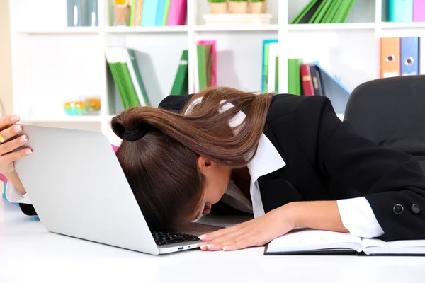 在她工作场所中的笔记本的女人累了的业务 — 图库照片