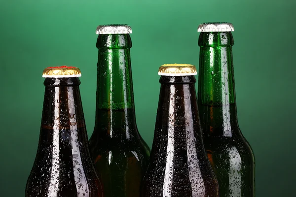 Gekleurd glas bierflessen op groene achtergrond — Stockfoto