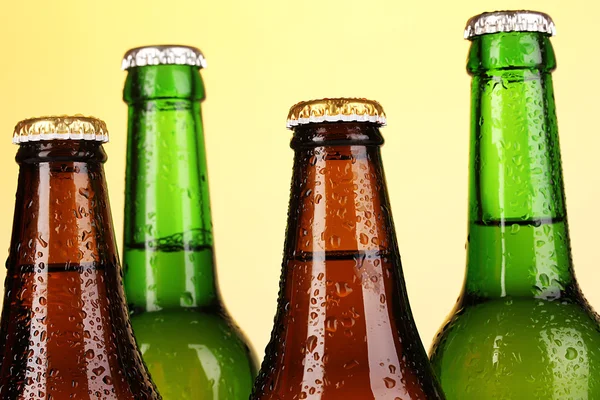 Kolorowe szkło butelek piwa na żółtym tle — Zdjęcie stockowe