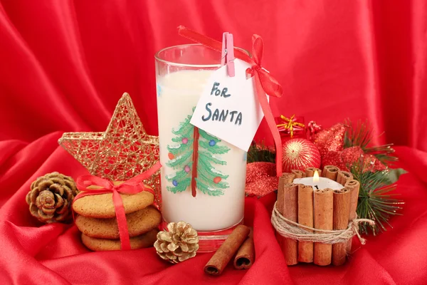 Galletas para Santa: Imagen conceptual de galletas de jengibre, leche y decoración navideña sobre fondo rojo — Foto de Stock