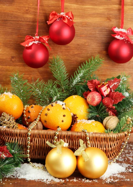 Christmas composition in basket with oranges and fir tree, on wooden background Stock Picture