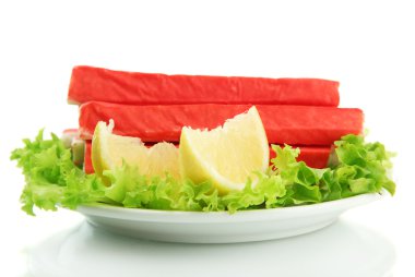 Yengeç sopalarla marul yaprakları ve plaka üzerinde beyaz izole limon