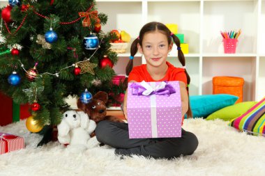 hediye kutusu Noel ağacının yakınında tutan küçük bir kız