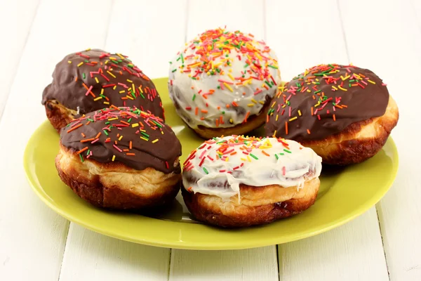 Velsmagende donuts på farveplade på lys træbaggrund - Stock-foto