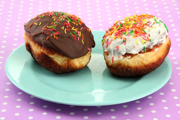 Смачні пончики на кольоровій тарілці на кольоровому фоні — стокове фото