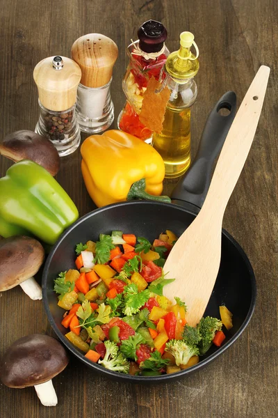 Legumes frescos fatiados em panela com especiarias e ingredientes em mesa de madeira — Fotografia de Stock