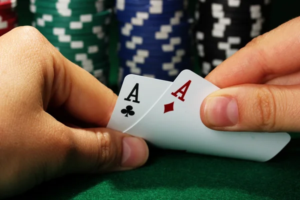 Chips en kaarten in handen op de groene tabel — Stockfoto