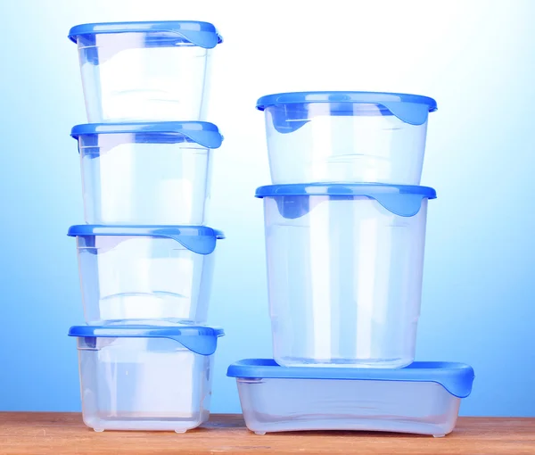 Plastic containers for food on wooden table on blue background — Stock Photo, Image