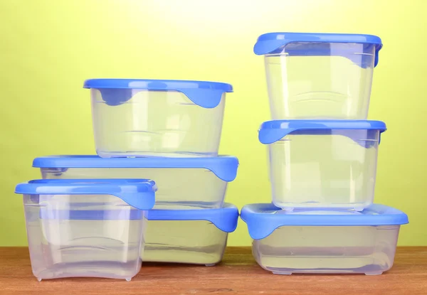 Recipientes de plástico para alimentos em mesa de madeira em fundo verde — Fotografia de Stock