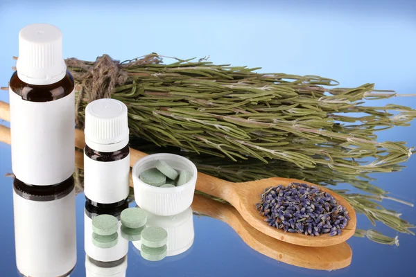 Garrafas de medicamentos e ervas no fundo azul. conceito de homeopatia — Fotografia de Stock