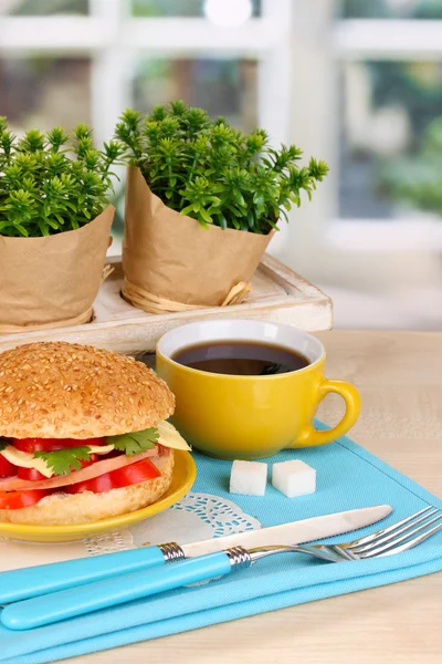 Smakelijk sandwich op kleurplaat op houten tafel op achtergrond van venster — Stockfoto