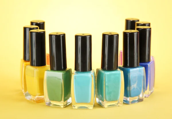 Grupo de esmaltes de uñas brillantes, sobre fondo amarillo — Foto de Stock
