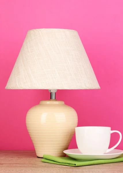 Table lamp and cup on pink background — Stock Photo, Image