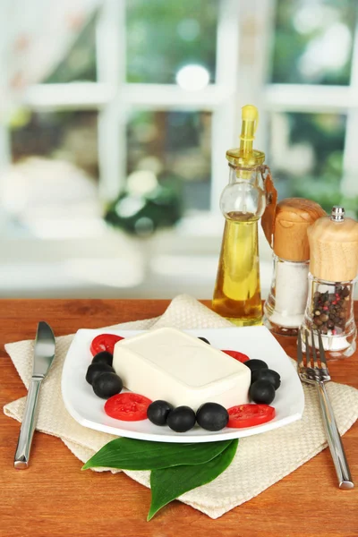 Queso feta en plato decorado con especias y aceite sobre mesa de madera sobre fondo de ventana — Foto de Stock