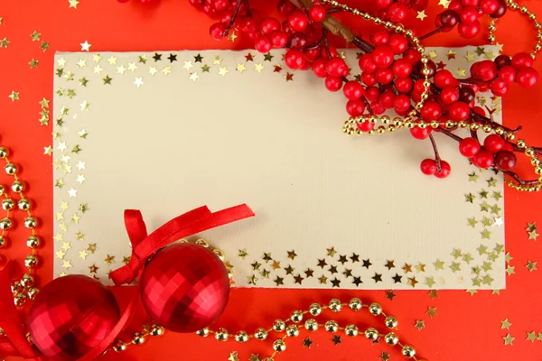 Belas bolas de Natal brilhantes e cartão postal vazio no fundo vermelho — Fotografia de Stock