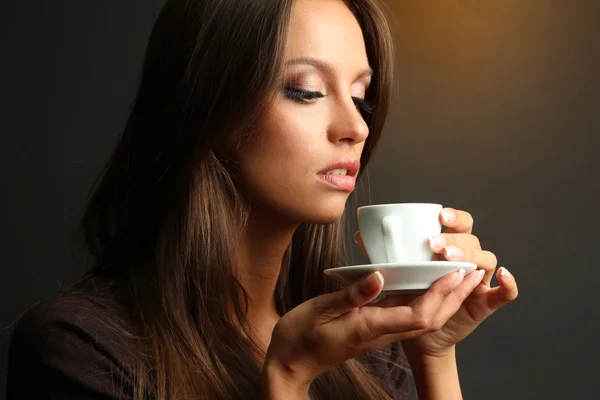 Bela jovem com xícara de café, no fundo marrom — Fotografia de Stock