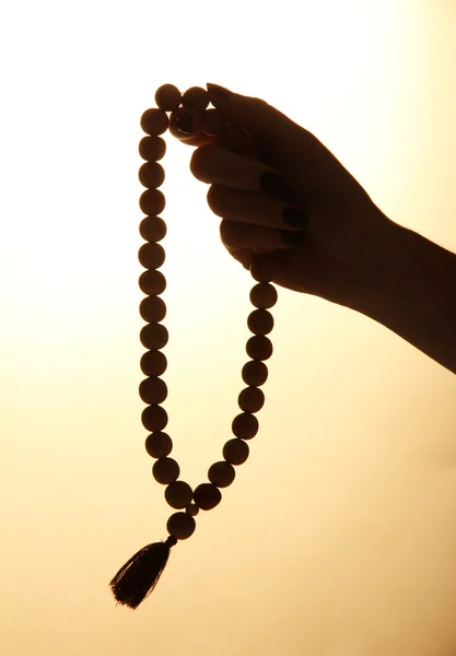 Mains féminines avec chapelet, sur fond beige — Photo