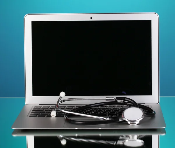 Stříbrný notebook s stetoskop na modrém pozadí s odleskem — Stock fotografie