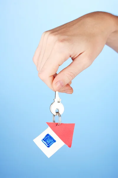 Hand holds key on blue background — Stock Photo, Image