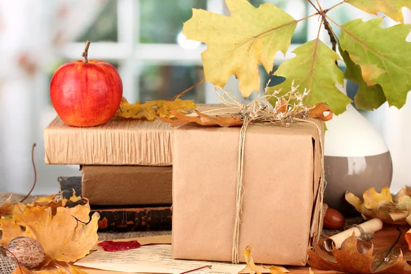 Autumnal composition with gift, books and leaves on bright background — Stock Photo, Image