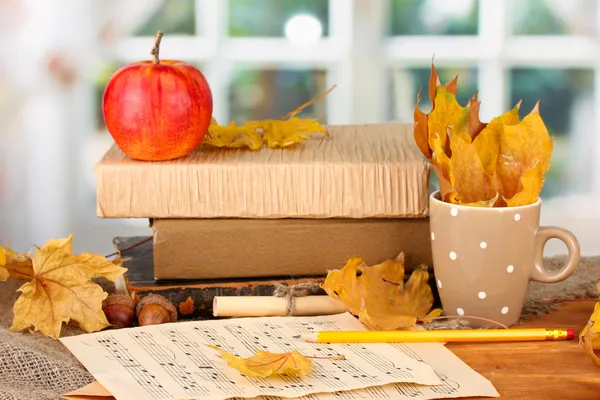 Autumnal composition with gift, books and leaves on bright background — Stock Photo, Image