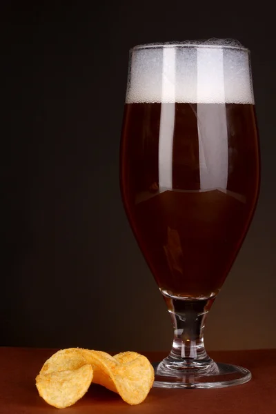 Verre de bière avec des frites sur fond brun — Photo