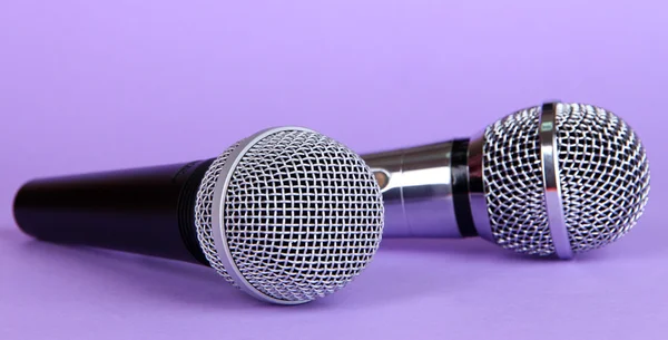 Srebrny i czarny mikrofony na fioletowym tle — Zdjęcie stockowe