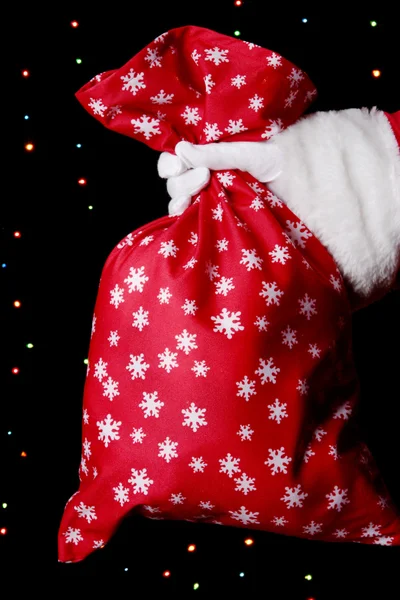 Weihnachtsmann Hand hält Tasche mit Geschenken auf hellem Hintergrund — Stockfoto