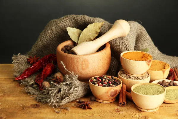 Mortar, bowls and spoons with spices, on table on grey background — Stock Photo, Image
