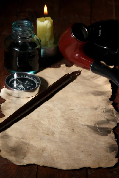 Old paper with ink pen, compass and cigar near lighting candle on wooden table — Stock Photo, Image