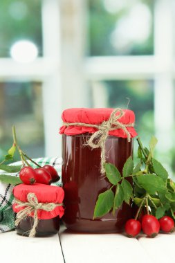kavanoz hip gül reçeli ve ahşap masa üzerinde olgunlaşmış meyveler