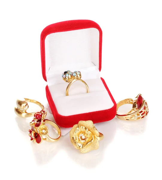 Anillo de oro con cristales azules, negros, lila y transparentes en caja de terciopelo rojo y cuatro anillos de oro aislados en blanco — Foto de Stock