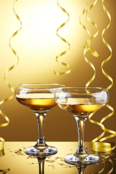 Glasses of champagne and streamer on yellow background — Stock Photo, Image