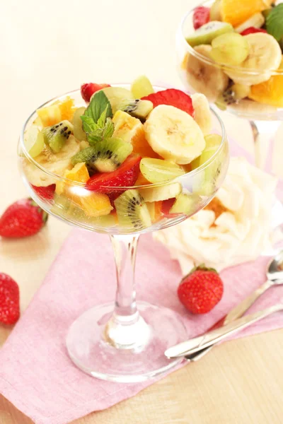 Fresh fruits salad and strawberries on wooden table — Stock Photo, Image