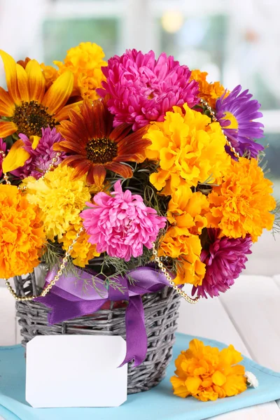Beautiful bouquet of bright flowers with paper note close-up on wooden table on window background — Stock Photo, Image