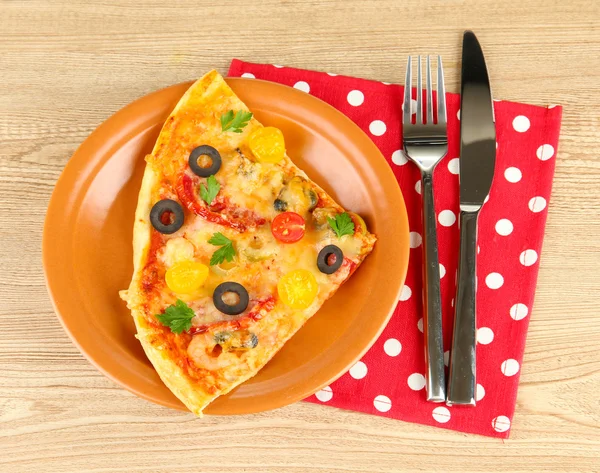 Plate with a slice of delicious pizza on wooden background — Stock Photo, Image