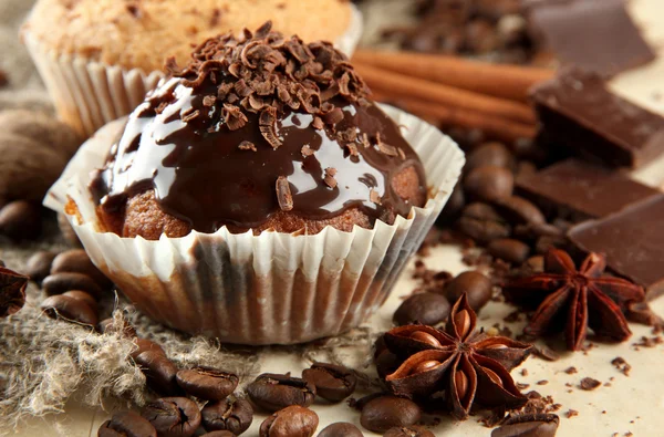 Smakelijke muffin taartjes met chocolade, specerijen en koffie zaden, op beige achtergrond — Stockfoto