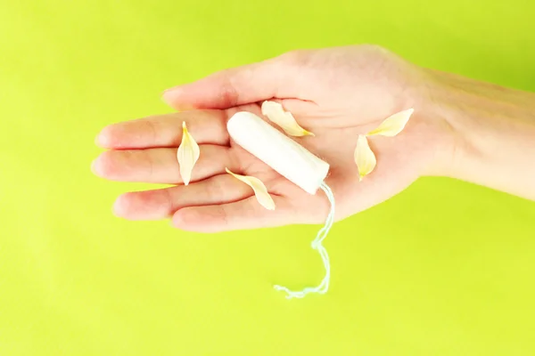 Woman's hand holding a clean cotton tampon on green background close-up — Stock Photo, Image