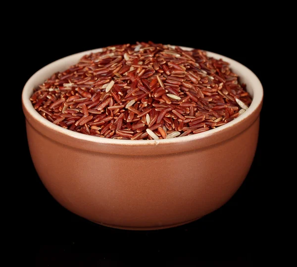 Red rice in brown bowl isolated on black — Stock Photo, Image