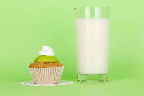 Glass of fresh new milk with cake on green background — Stock Photo, Image