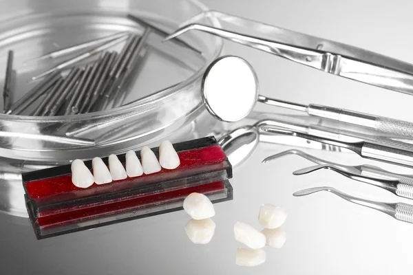 Juego de herramientas dentales con dentadura postiza sobre fondo gris — Foto de Stock