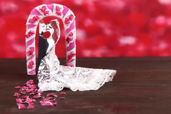 Dekorative verheiratete Liebespaar auf Holztisch auf rotem Hintergrund — Stockfoto