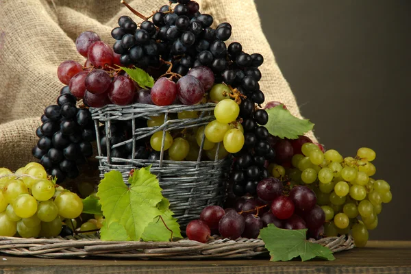 Assortment of ripe sweet grapes in basket, on grey background — Stock Photo, Image