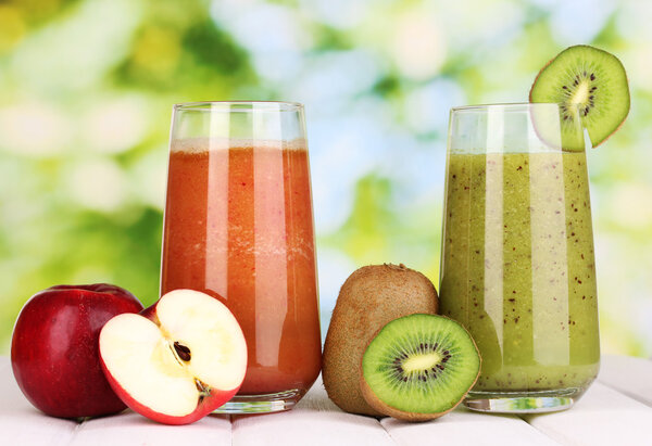 fresh fruit juices on wooden table, on green background