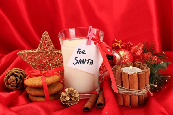 Kekse für den Weihnachtsmann: Konzeptbild von Ingwerplätzchen, Milch und Weihnachtsdekoration auf rotem Hintergrund — Stockfoto
