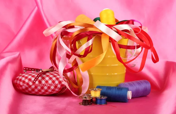 Χρώμα κάδου με πολύχρωμες κορδέλες και κλωστές σε φόντο ροζ ύφασμα — Φωτογραφία Αρχείου