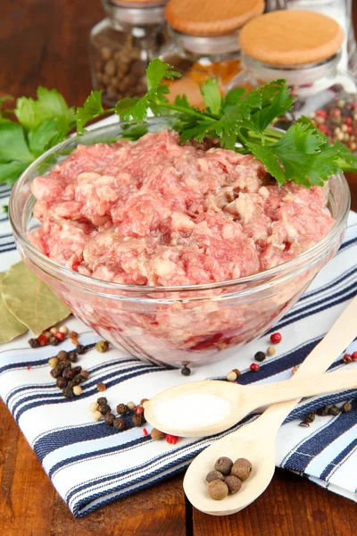 Bowl of raw ground meat with spices on wooden table Stock Photo