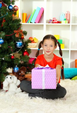 hediye kutusu Noel ağacının yakınında tutan küçük bir kız