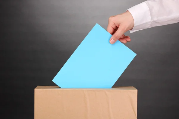 Hand with voting ballot and box on grey background — Stock Photo, Image